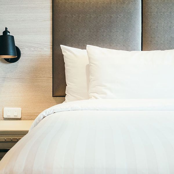 A neatly made white bed with a white pillow and a black nightstand, showcasing bed and breakfast accommodation design.
