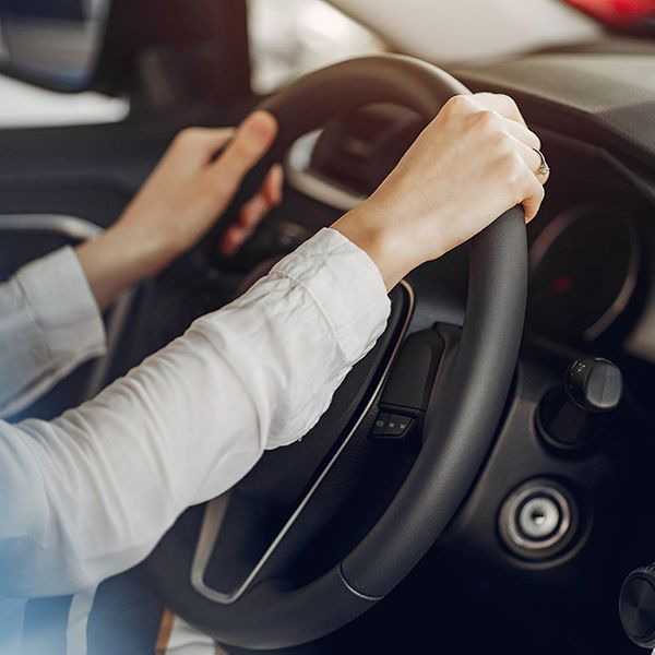 A woman with her hands on the steering wheel, driving a car, illustrating car rental company website design.