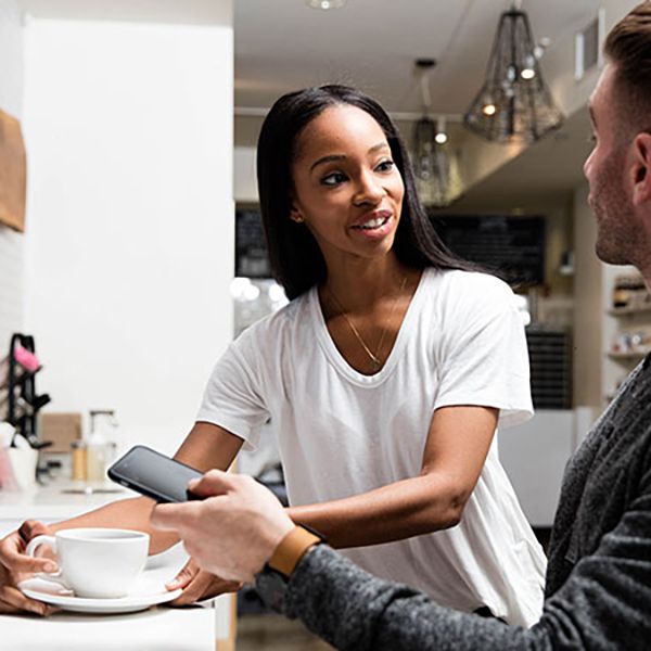 A man and woman pose in front of a coffee shop, highlighting the inviting design for the Cafe & Deli website.