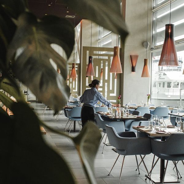 A restaurant with blue chairs and a woman in front, illustrating a stylish website design concept.
