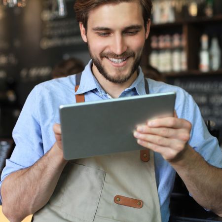 man at a bar taking an order on an ipad